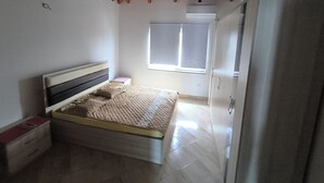 Quarto com cama, guarda-roupa, janela e teto com vigas de madeira.