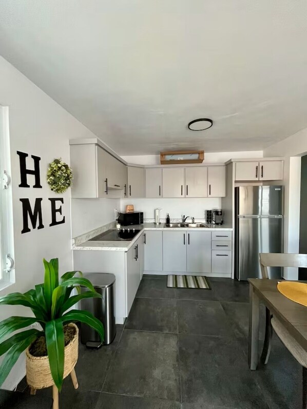 A modern kitchen with white cabinets, stainless steel appliances, and a grey tiled floor.