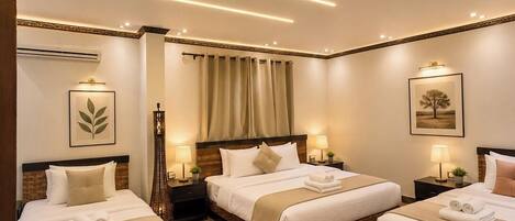 A hotel room with three beds, a large window with curtains, a wooden floor, and modern lighting.