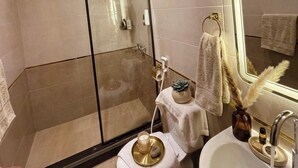 A modern bathroom with a glass-enclosed shower, a white sink with a mirror, and a towel rack. - Foola Pyramids Inn Hotel (Giza)