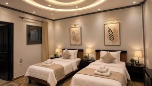 A hotel room with two beds, a circular ceiling light design, and a wooden floor. - Foola Pyramids Inn Hotel (Giza)