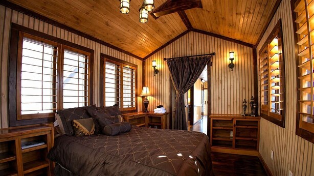 A wooden-paneled room with a large bed, built-in shelves, and a view through a window. - Pet-Friendly Chateau with Hot Tub (Sugar Mountain)