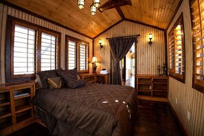A wooden-paneled room with a large bed, built-in shelves, and a view through a window. - Pet-Friendly Chateau with Hot Tub (Sugar Mountain)