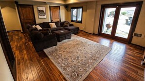A spacious living room with a large sectional sofa, a patterned rug, and hardwood flooring. - Pet-Friendly Chateau with Hot Tub (Sugar Mountain)