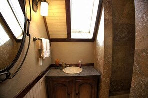 Ein Badezimmer mit Dachfenster, Waschbecken, Handtuchhalter und einem Holzschrank.