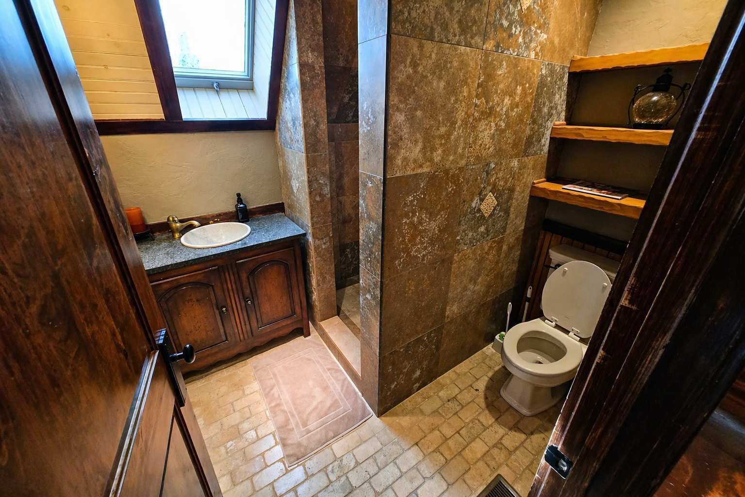 A bathroom with a wooden vanity, a sink, a toilet, and a shower area.