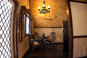 Una stanza con rivestimenti in legno, un tavolo da pranzo con sedie, un lampadario e una finestra con tende.