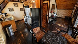 Una cocina acogedora con armarios de madera, un refrigerador y un lavabo. Hay una zona de comedor con una mesa y sillas.