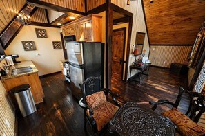 A cozy kitchen with wooden cabinets, a refrigerator, and a sink. There is a dining area with a table and chairs. - Pet-Friendly Chateau with Hot Tub (Sugar Mountain)