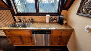 A kitchen with a double sink, stainless steel dishwasher, and a coffee maker. - Pet-Friendly Chateau with Hot Tub (Sugar Mountain)