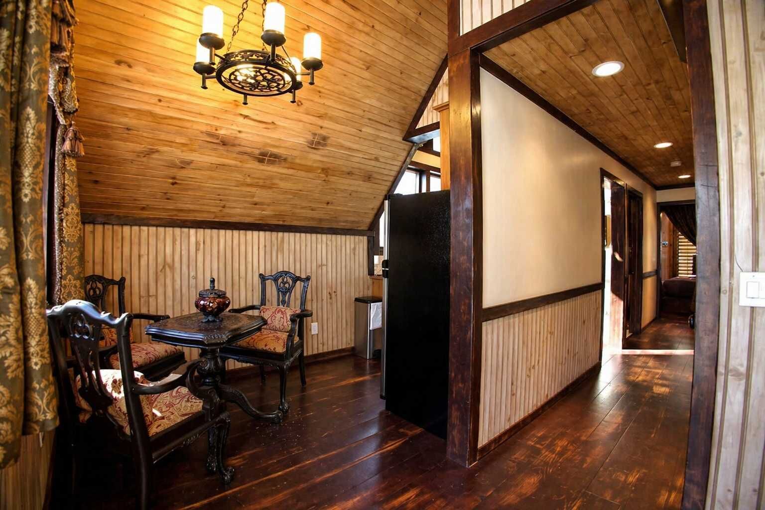 A wooden interior with a dining area, a chandelier, and a hallway leading to another room.