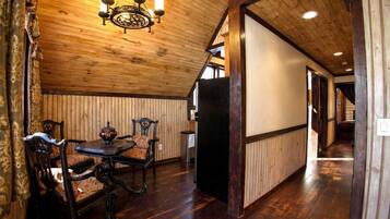 A wooden interior with a dining area, a chandelier, and a hallway leading to another room.