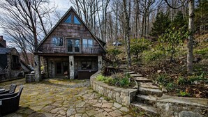 A stone-paved courtyard with a wooden house, stone steps, and a hot tub. - Pet-Friendly Chateau with Hot Tub (Sugar Mountain)
