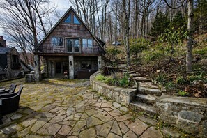 Une cour dallée de pierres, avec une maison en bois, des marches en pierre et un jacuzzi.