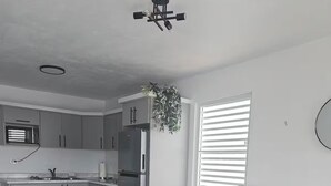 Una cocina moderna con armarios grises, un refrigerador de acero inoxidable, una mesa de centro de madera y un sofá gris.