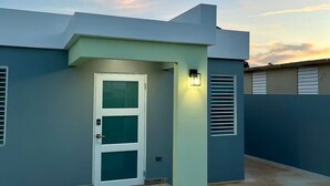Un edificio moderno con techo plano, una puerta blanca y un pequeño porche.
