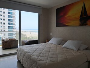 A bedroom with a large bed, a view of the beach, and a cityscape through the window. - Premium  frente al mar Acceso a la playa (Cartagena)