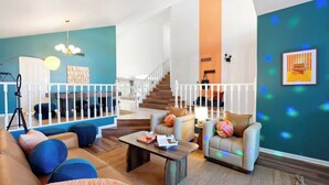 A modern living room with a staircase, a sofa, a coffee table, and a view of the upper floor. - Desert Daze • A Fun-Filled 5BR Retreat • Sleeps 12 (Mesa)
