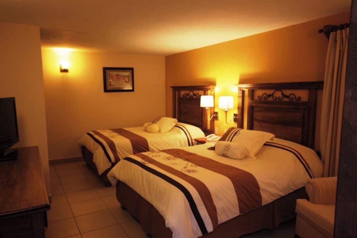A hotel room with two beds, a television, and a desk.