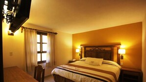 Ein Hotelzimmer mit Bett, Nachttischen, einem Schreibtisch und einem Fernseher.