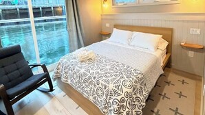 Une chambre d’hôtel avec un lit, une chaise, une fenêtre avec des rideaux et une vue sur l’extérieur.