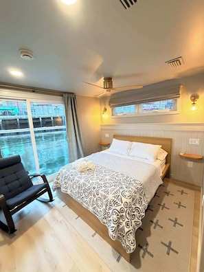 Habitación de hotel con cama, una silla, ventana con cortinas y vistas al exterior.