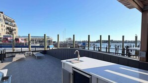 Un bar situé sur le toit, offrant une vue sur le port de plaisance, avec un évier et des places assises en plein air.