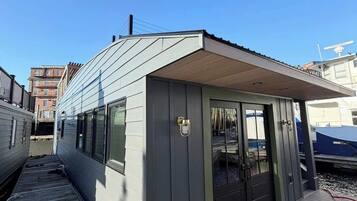 Ein kleines, eingeschossiges Gebäude mit Flachdach, einer Tür mit Fenster und einer kleinen Veranda.