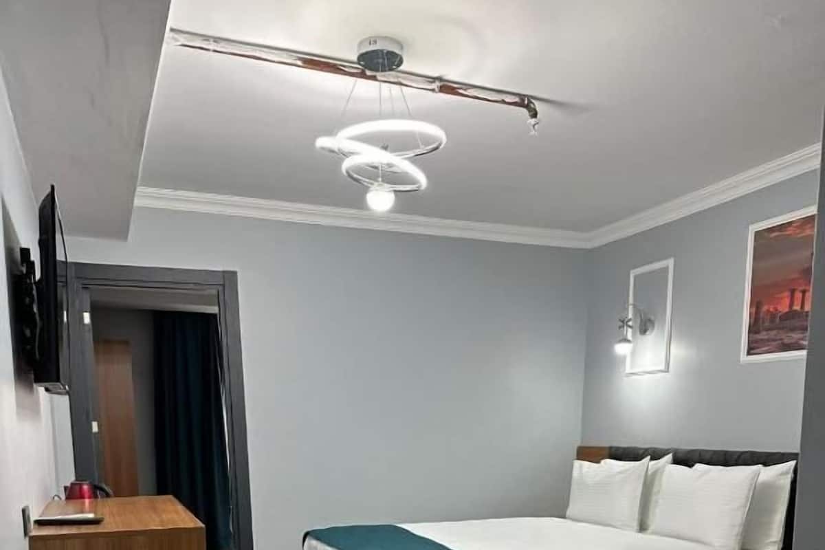 Ein Hotelzimmer mit zwei Betten, einem Schreibtisch, einem Flachbildfernseher und einer Deckenleuchte.