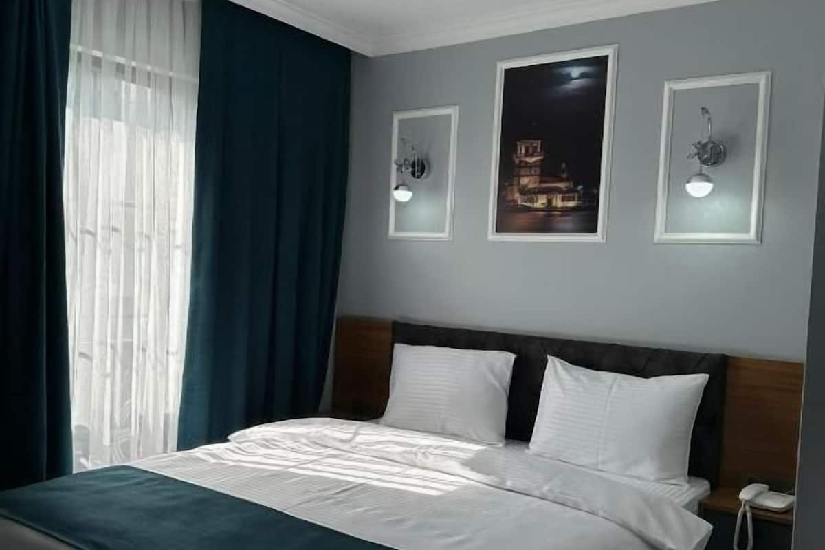 Ein Hotelzimmer mit einem Bett, einem Nachttisch mit Telefon und zwei Wandleuchten.