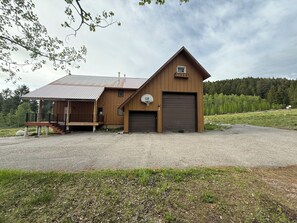 Ein zweistöckiges Holzhaus mit einer Veranda, einem Basketballkorb und einer Garage.
