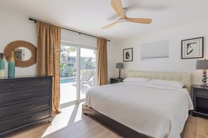A bedroom with a bed, a ceiling fan, a nightstand, a lamp, a dresser, and a view of the outside. - P85 - New Listing! Be the First to Stay in This 3BR Pool Home (Marthon)