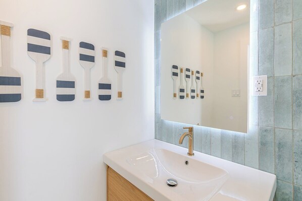 A bathroom with a white sink, a gold faucet, and a mirror with a lighted frame. - P85 - New Listing! Be the First to Stay in This 3BR Pool Home (Marthon)