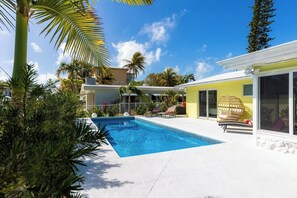 A swimming pool with lounge chairs, a yellow building, and palm trees. - P85 - New Listing! Be the First to Stay in This 3BR Pool Home (Marthon)