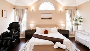 Ein modernes Hotelzimmer mit einem großen Bett, einem Massagesessel, einem kleinen Tisch und einem Fenster mit Vorhängen.