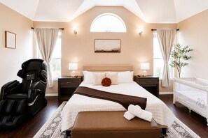 A modern hotel room with a large bed, a massage chair, a small table, and a window with curtains. - FIFA Traveler's Oasis Pool Sauna Patio Arcade Sleep 14+ (Richmond)