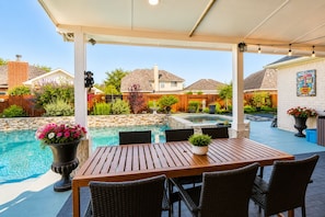 A covered outdoor area with a pool, a wooden table with chairs, and potted plants. - FIFA Traveler's Oasis Pool Sauna Patio Arcade Sleep 14+ (Richmond)