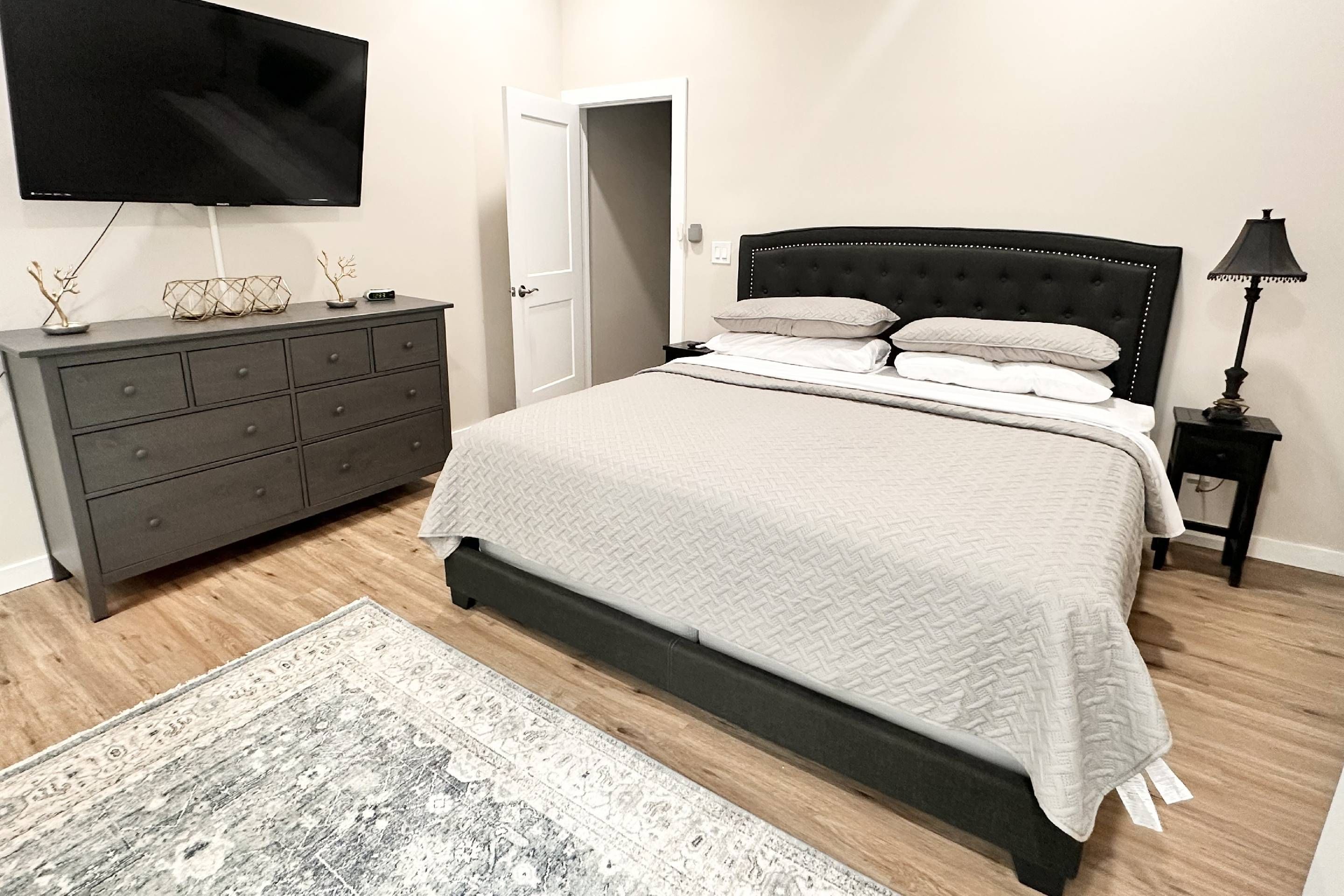 Une chambre à coucher avec un lit, une commode, une télévision et une porte.
