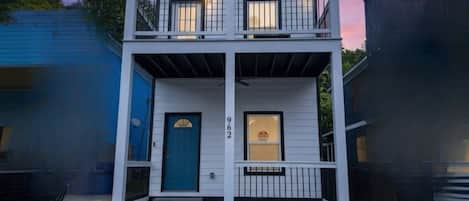 Una casa de dos pisos con una puerta azul, un balcón y el número 962 en la fachada.