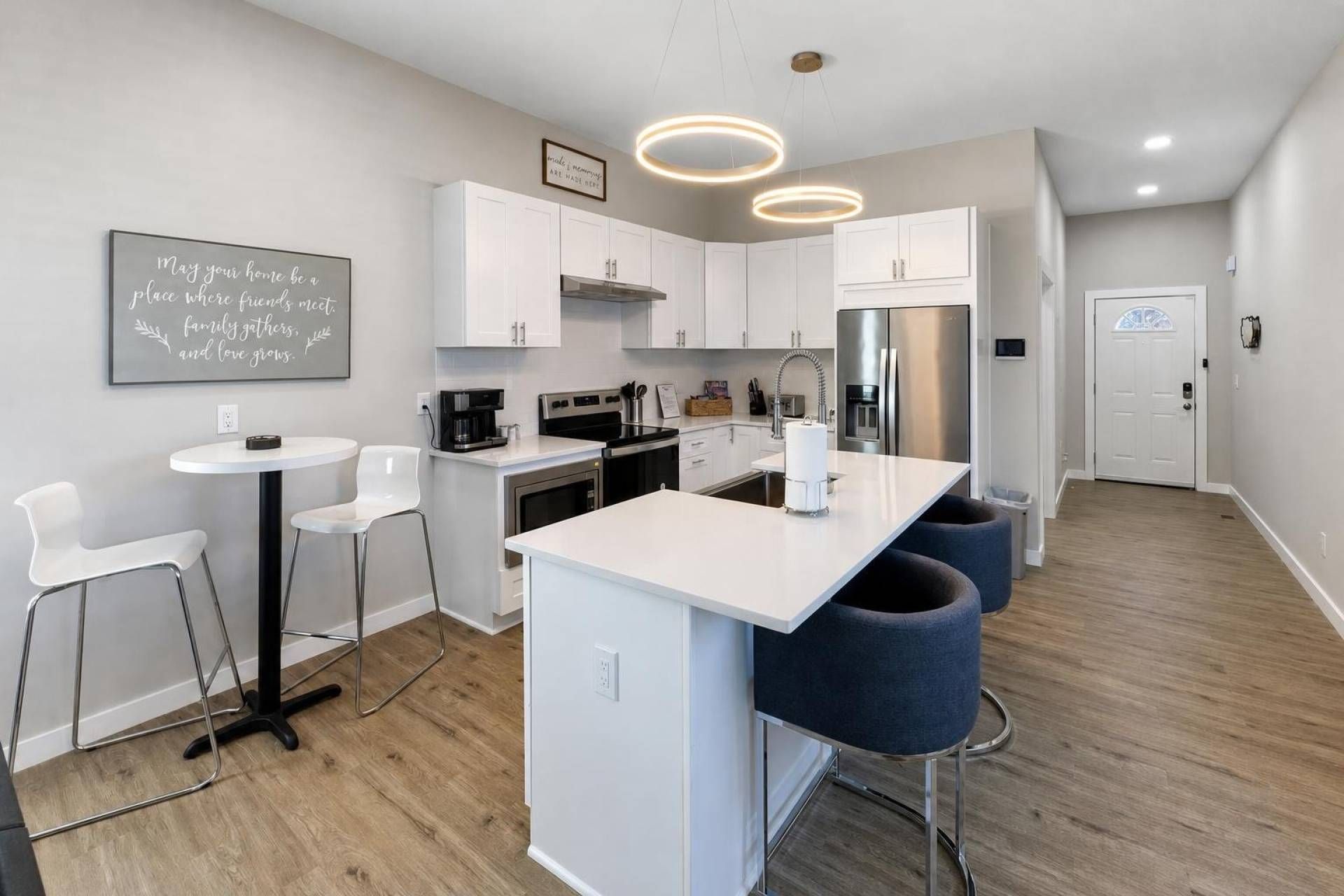 Une cuisine moderne avec des meubles blancs, un îlot central et des tabourets de bar.