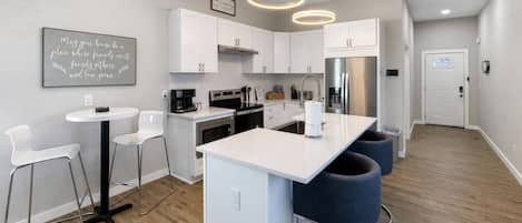 Une cuisine moderne avec des meubles blancs, un îlot central et des tabourets de bar.
