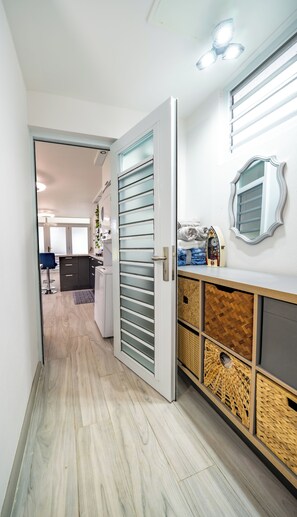 A hallway with a wooden floor, a sliding glass door, a mirror, and a small kitchen area with a refrigerator. - Peaceful 1-bedroom apartment with AC in beautiful Isabela (Isabela)