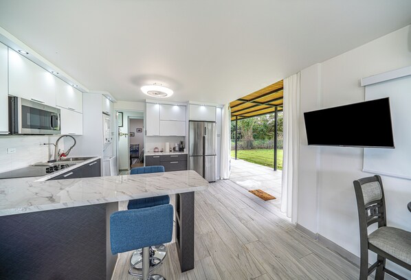 A modern kitchen with a marble countertop, stainless steel appliances, and a large window. - Peaceful 1-bedroom apartment with AC in beautiful Isabela (Isabela)