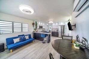 A modern kitchen with a central island, a dining area with a dark wood table, and a blue sofa with patterned cushions. - Peaceful 1-bedroom apartment with AC in beautiful Isabela (Isabela)
