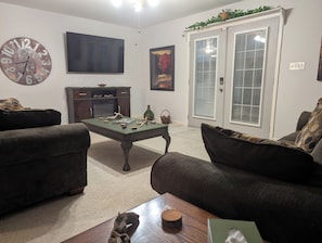 A living room with two sofas, a coffee table, a TV, a fireplace, and a door with blinds.