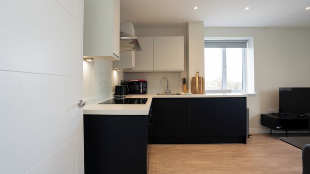 Una cocina moderna con gabinetes negros, una encimera negra, una cafetera y un ventanal.