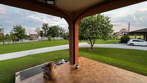 Eine überdachte Terrasse mit Backsteinboden, einem Blumentopf und einer dekorativen Schale.