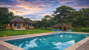 A rectangular swimming pool with a tiled edge, surrounded by hexagonal paving. - The Hedge Cottages (Konkola)