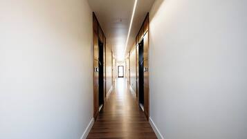 A long, narrow hallway with wooden flooring and walls, leading to a door at the end.