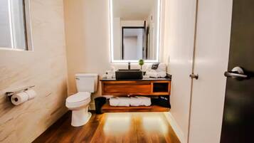 A bathroom with a toilet, a sink, a mirror, and a wooden vanity.